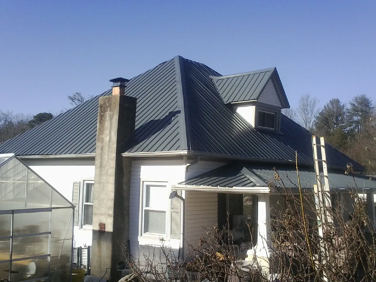 Dark blue standing seam metal roof on a white farmhouse with dormer — Slate & Tile Roof Repair by Roofing Brothers in Aredale