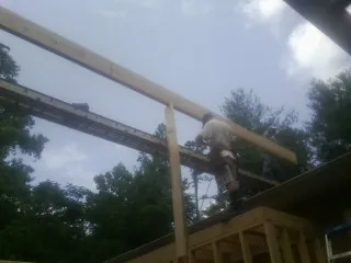 Carpenter setting a ridge beam over a new addition frame — Ice Dam Removal by Roofing Brothers in Aredale