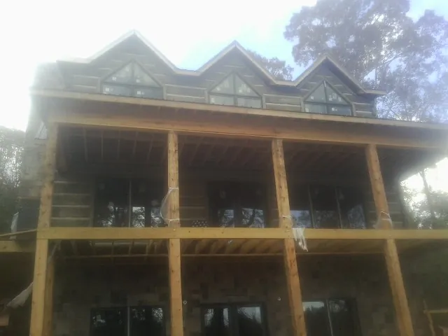 Dormers and porch framing on a large log home under construction — Roof Coating work by our crew in Aredale