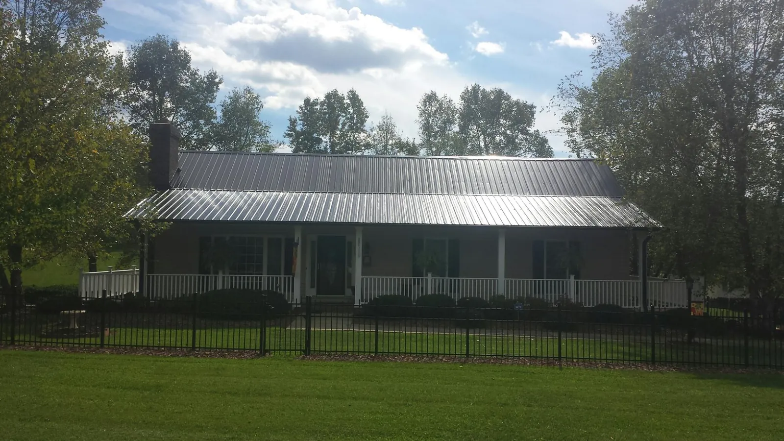 Gray metal roof on a brick ranch with a full width front porch in Aredale