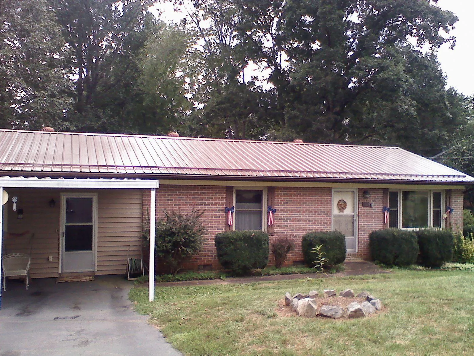 Bronze metal roof and carport on a brick ranch home — Roof Repair work by our crew in Aredale