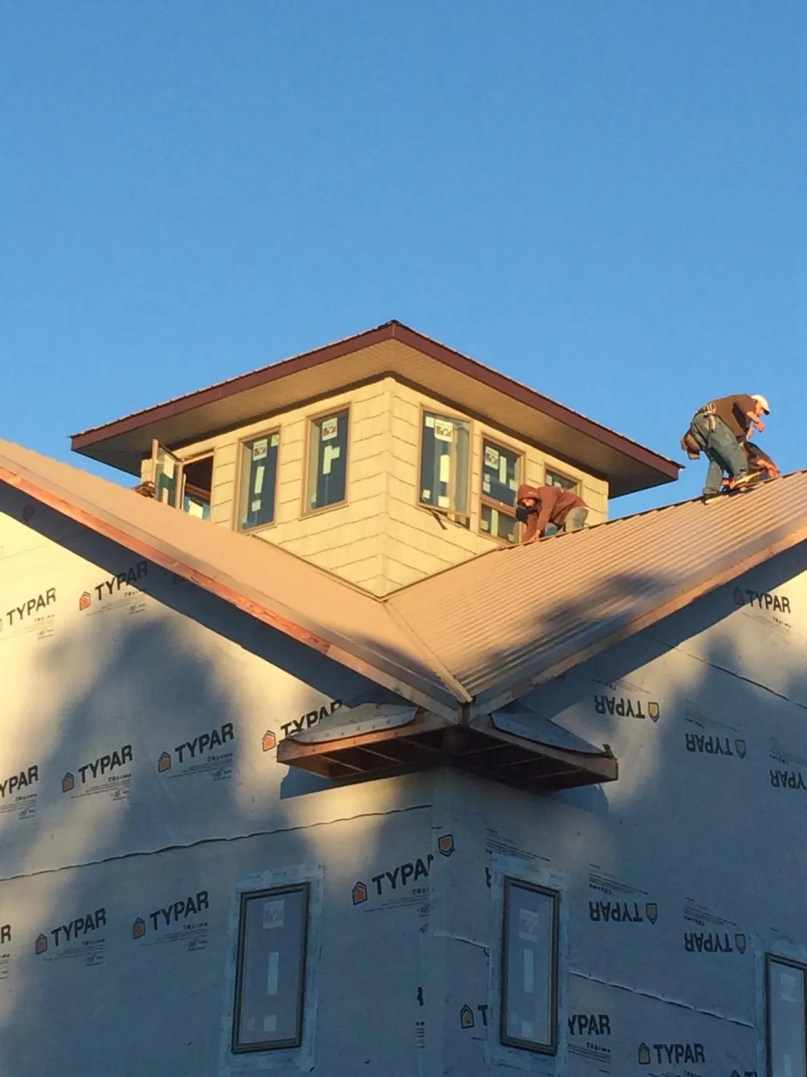 Roofers working around a rooftop cupola on a new metal roof at sunset — Roof Waterproofing in Aredale by Roofing Brothers